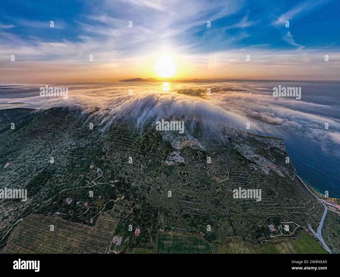Sicilia 2023. Nuvole che si arrampicano sul Monte Santa Caterina sull'isola di Favignana. Dietro vediamo il sole all'alba. Luglio 2023 Trapani, Italia Foto Stock