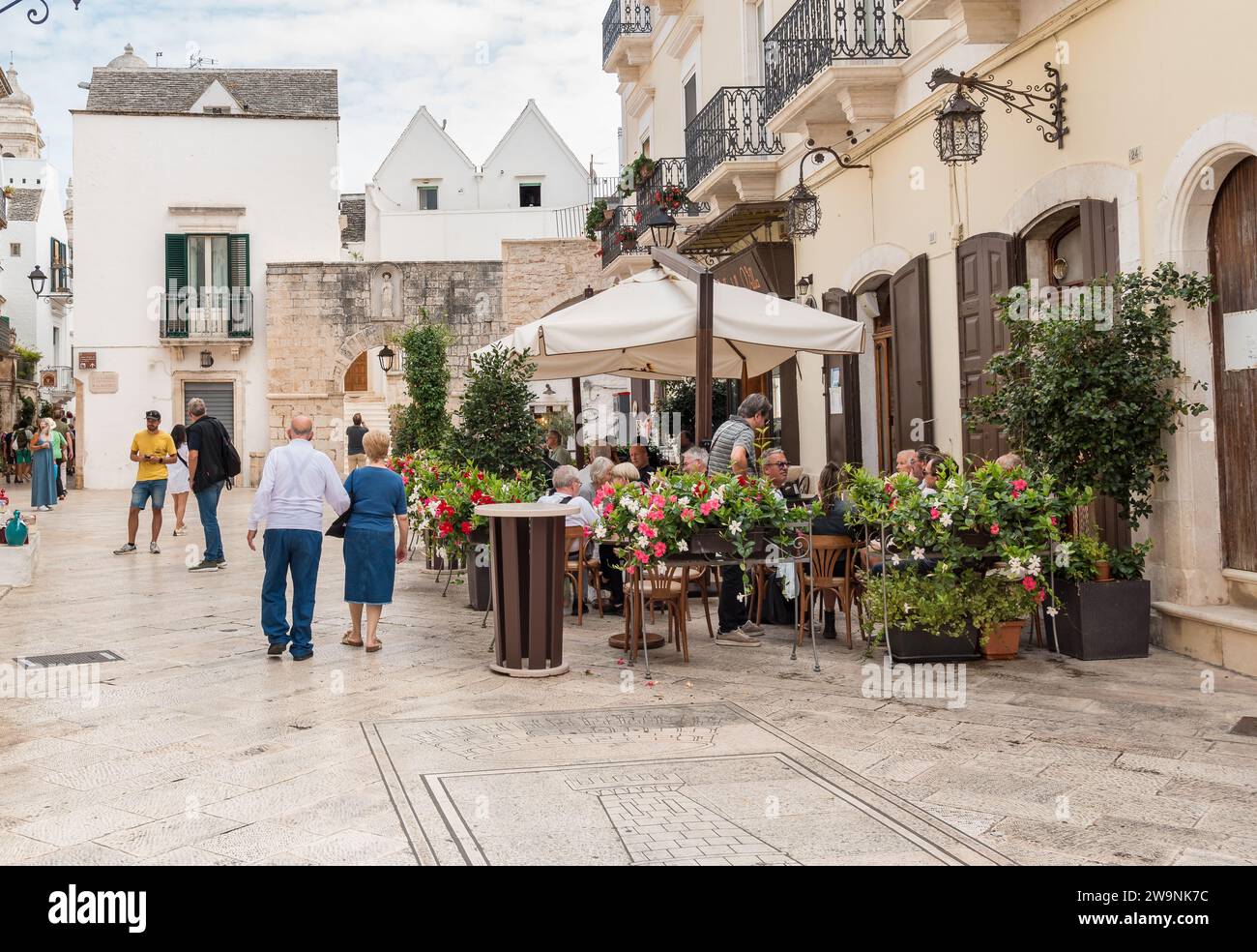 Locorotondo, Puglia, Italia - 5 ottobre 2023: I turisti si godono i ristoranti all'aperto nell'antico borgo di Locorotondo, in provincia di Bari. Foto Stock