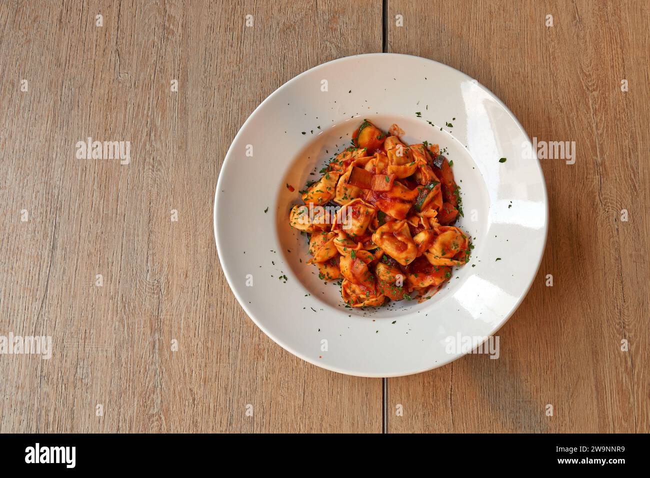 Tavola ruvida in legno con un piatto di ravioli bolognesi Foto Stock