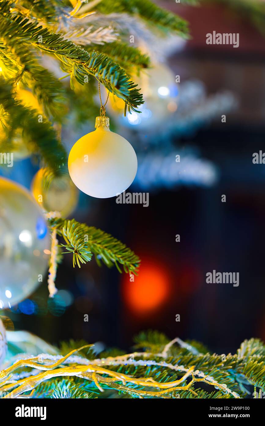 Immergetevi nello spirito delle vacanze con questa incantevole foto con baubles su un'abete caucasica. Luci di Natale sfocate e decorazioni natalizie ne esaltano l'aspetto Foto Stock