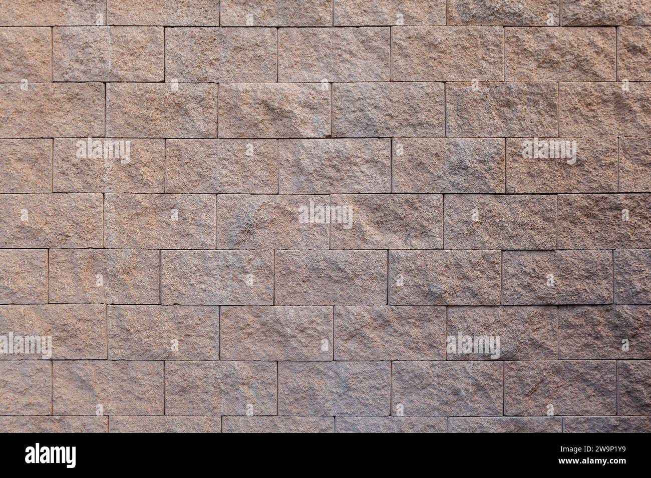 Una vista dettagliata di un muro di mattoni di arenaria che mostra la consistenza naturale e il motivo delle pietre. Foto Stock