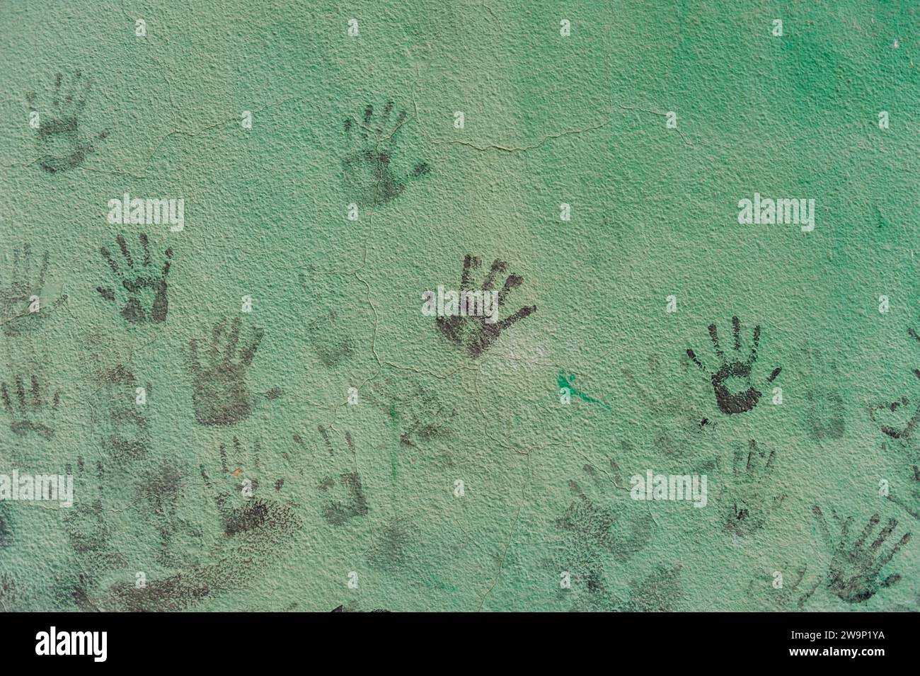 Un muro dipinto di verde conserva il ricordo giocoso delle impronte delle mani dei bambini sparse sulla sua superficie. Foto Stock