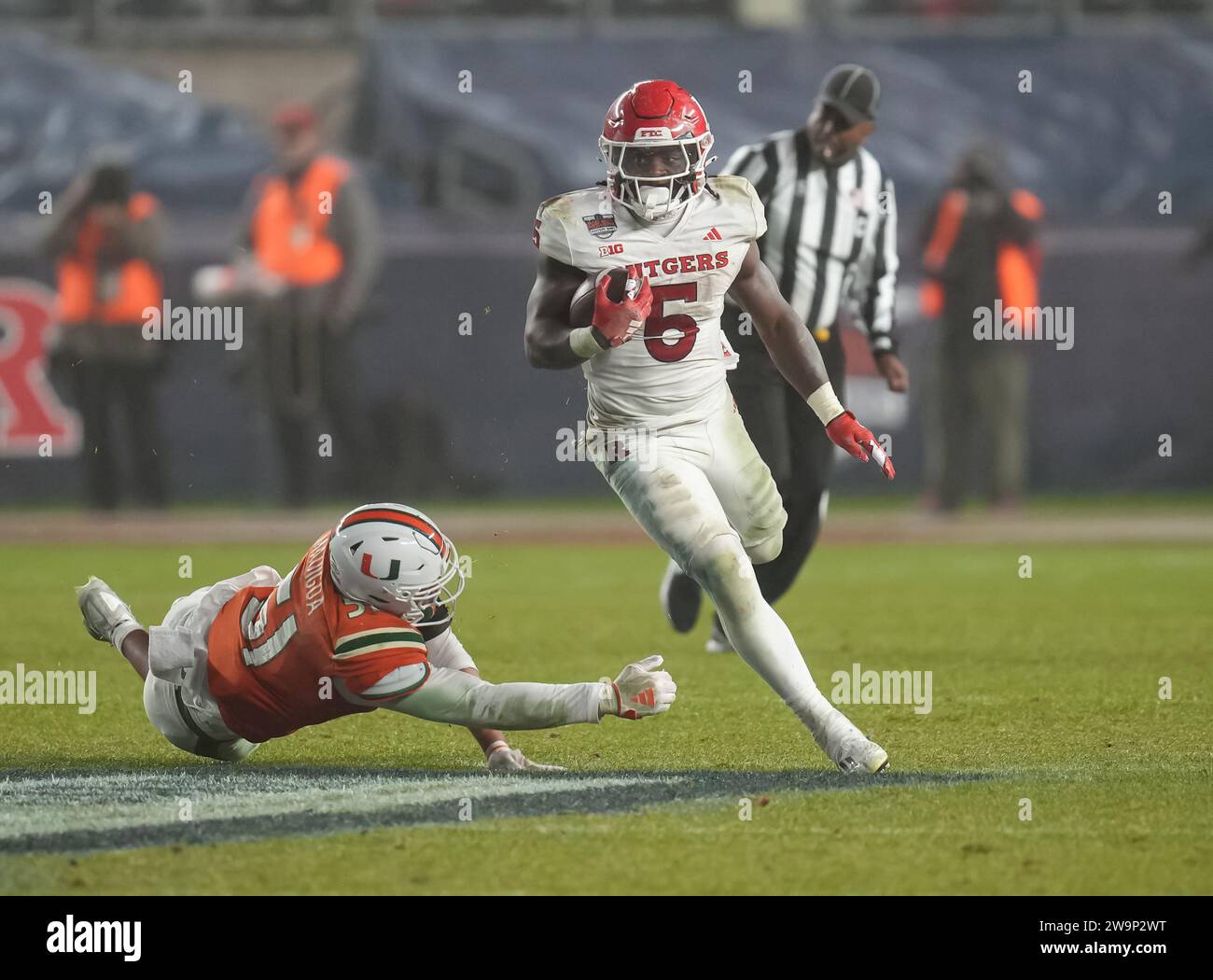 Il running back dei Rutgers Scarlet Knights Kyle Monangai (5) corre sul campo mentre il linebacker dei Miami Hurricanes Francisco Mauigoa (51) si tuffa per cercare di afferrarlo durante la partita di football universitario dei Boy Mowers Pinstripe Bowl del terzo periodo tra i Rutgers Scarlet Knights e i Miami Hurricanes il 28 dicembre 2023 allo Yankee Stadium nel Bronx, New York. Rutgers batte Miami 31-21 (David Venezia / immagine dello sport) Foto Stock