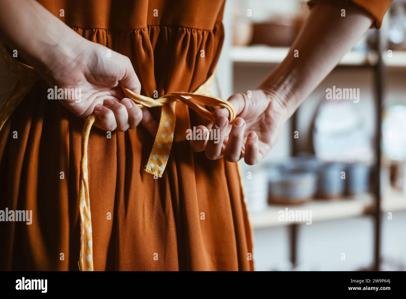 Potter Woman si prepara al lavoro mettendo il grembiule Foto Stock