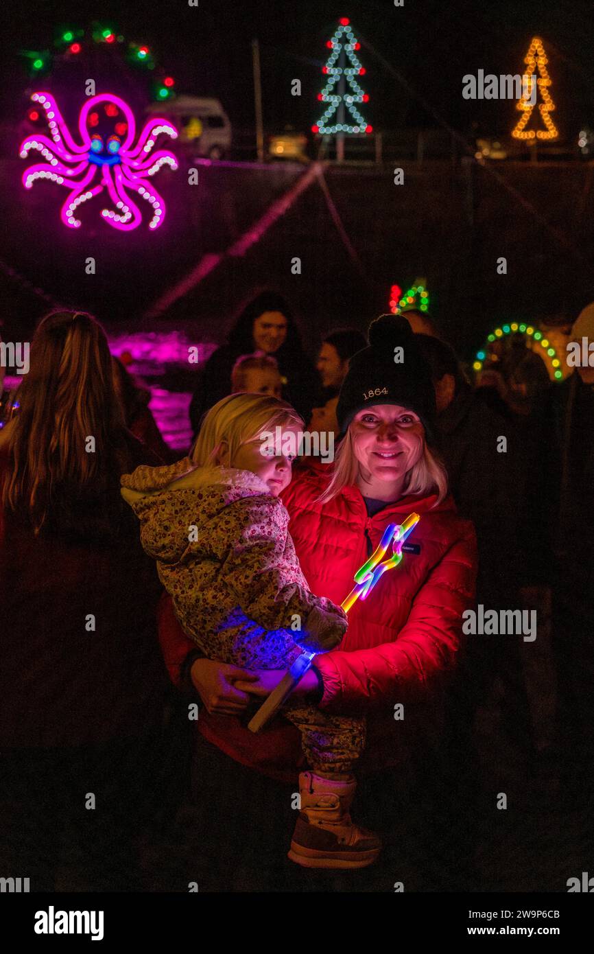 Una madre e un bambino si divertono con le luci del porto, un'esposizione annuale di luci natalizie nel piccolo villaggio costiero di Mousehole, Cornovaglia, Regno Unito Foto Stock