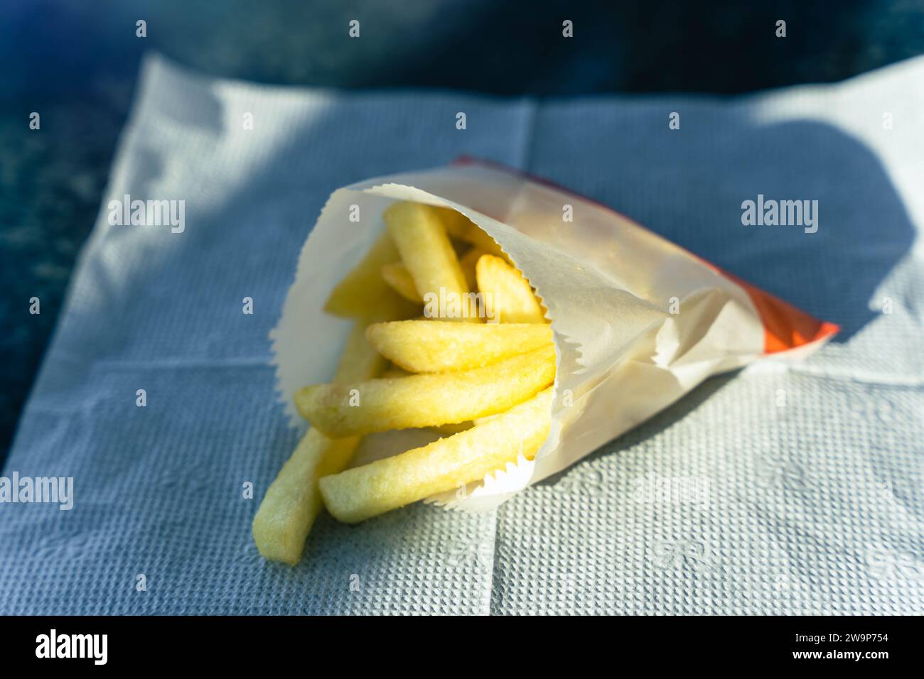 Patatine fritte dorate e croccanti servite in una classica tazza di carta, ideale per gli appassionati di fast food. viziatevi con una delizia deliziosa. Foto Stock