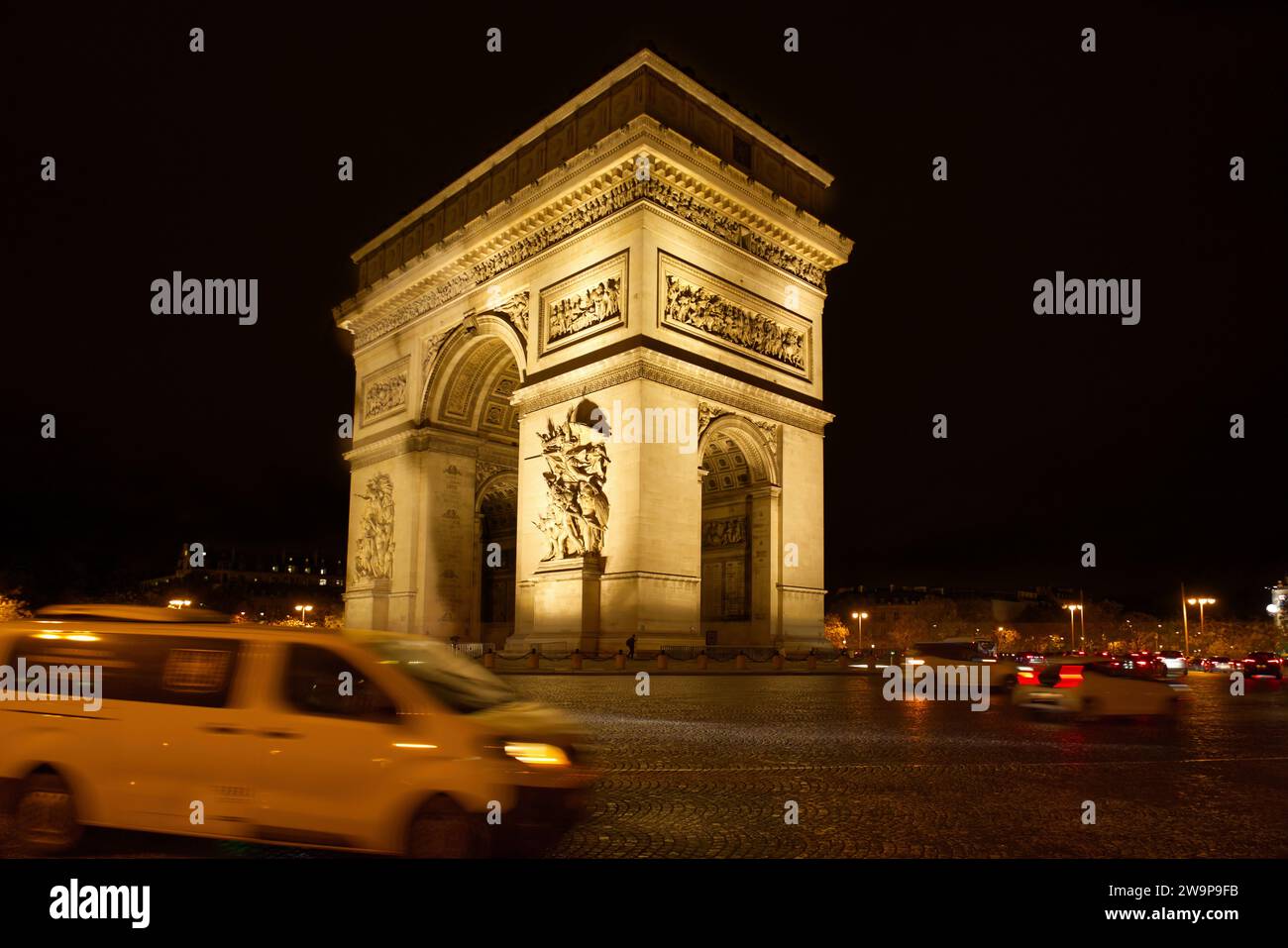 Place Charles de Gaulle o Place de l'Étoile, Parigi, Francia - Arco di Trionfo monumento con auto che lo circondano di notte Foto Stock