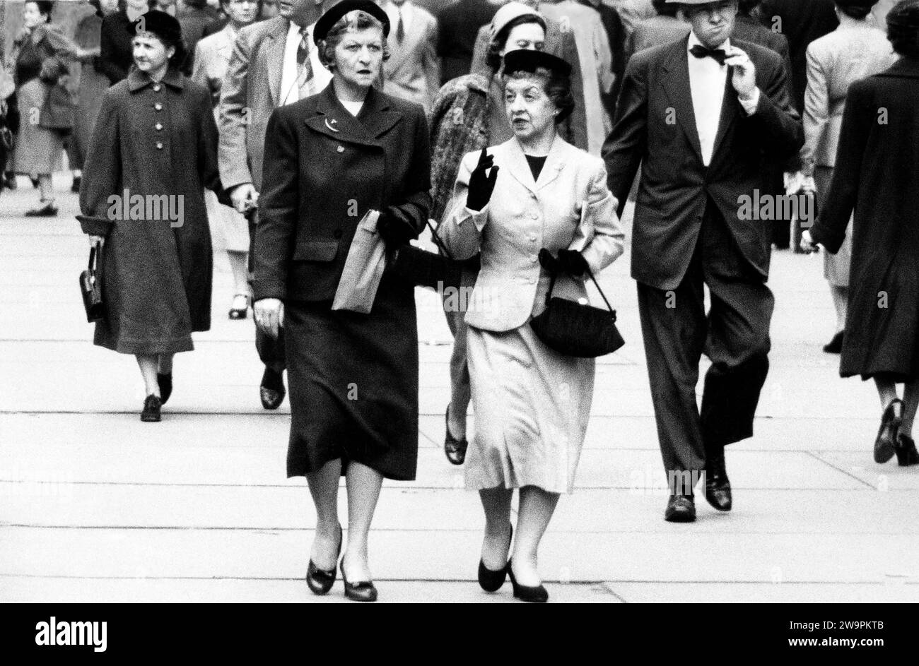 Due donne che parlano mentre camminano sul marciapiede, New York City, New York, USA, Angelo Rizzuto, Anthony Angel Collection, ottobre 1953 Foto Stock
