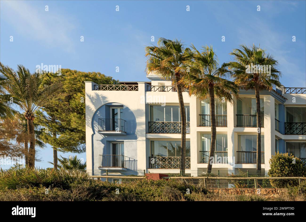 Edificio dipinto di blu e bianco a tre piani circondato da vegetazione tropicale e palme Foto Stock