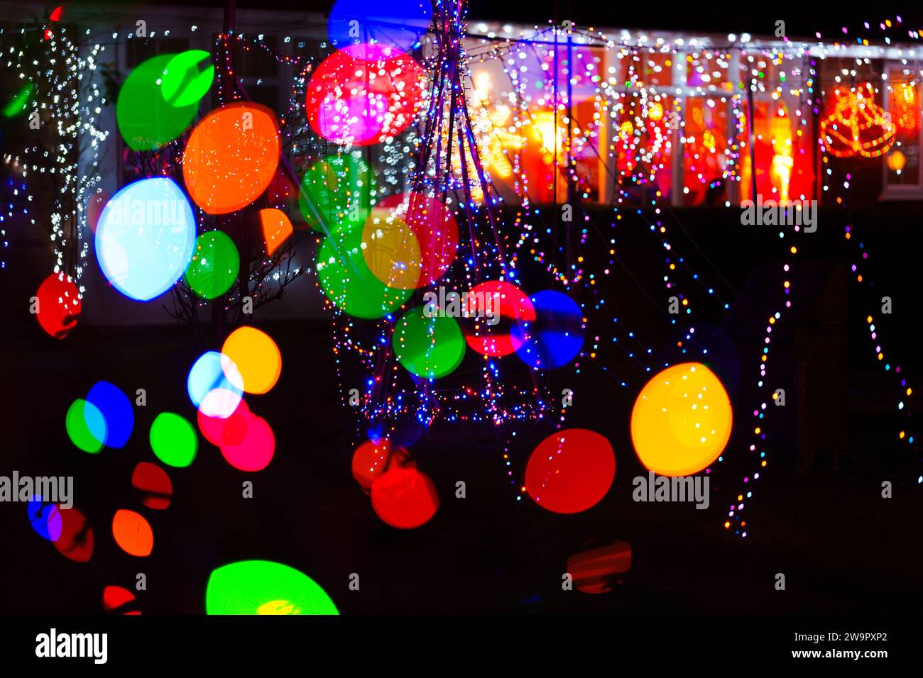 L'immagine di un albero senza foglie con magiche luci colorate di natale e grandi palline di bokeh a colori casuali. Sfondo natalizio. Copia spa Foto Stock