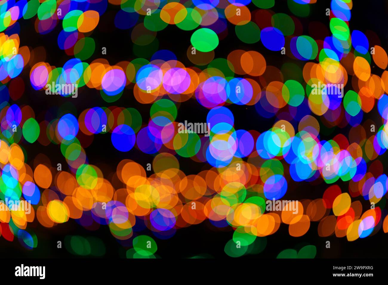 Grandi palline bokeh verdi, rosse, arancioni e blu che girano e creano un ornamento magico. Sfondo astratto ad alta risoluzione. Foto vera. Foto Stock