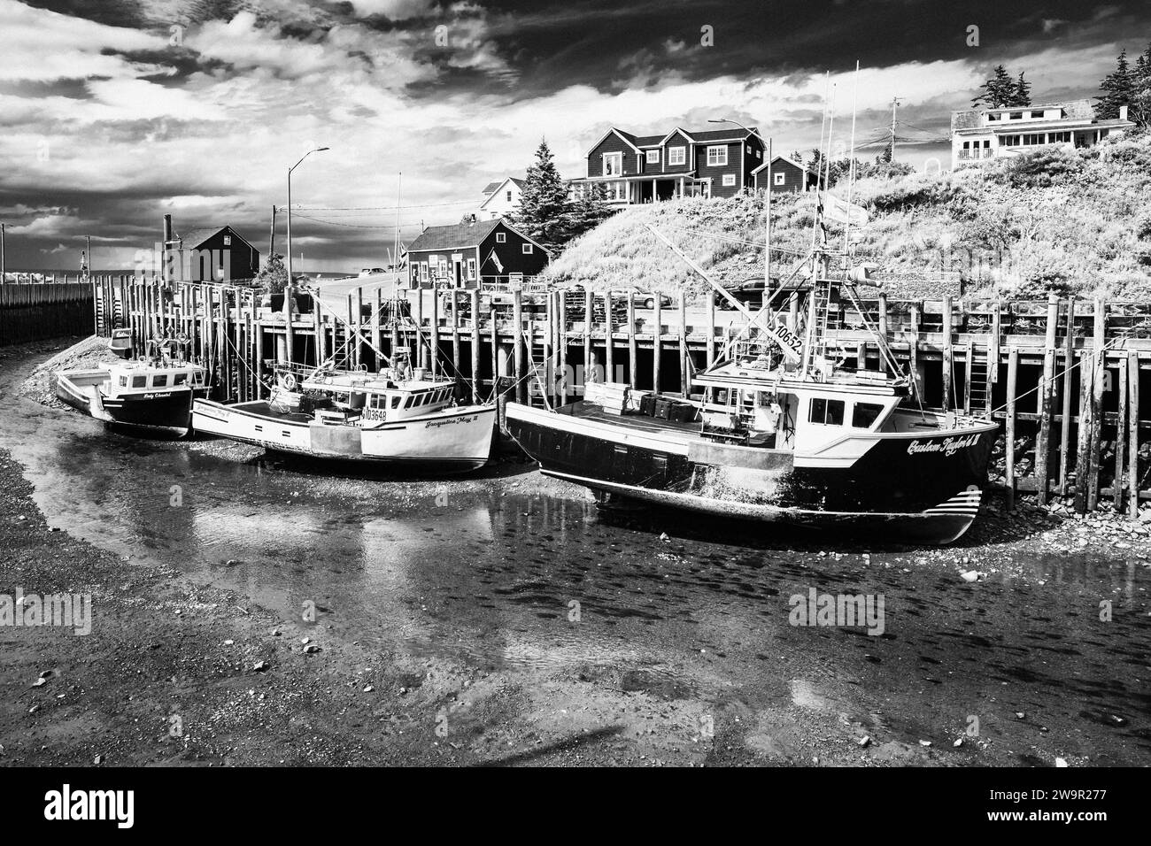 Barche da pesca con bassa marea lungo un molo a Halls Harbour, nuova Scozia, Canada. Foto Stock