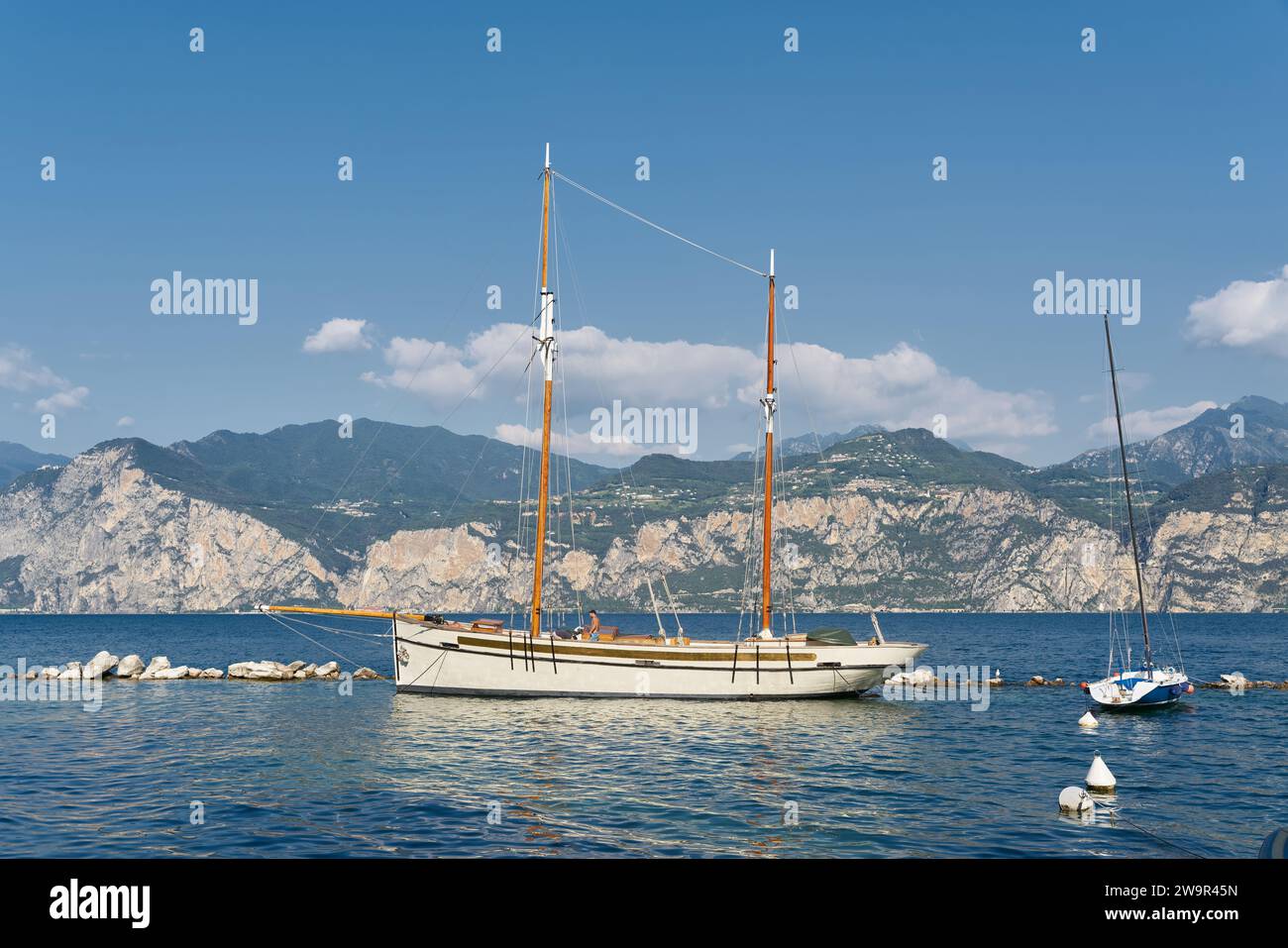 Yacht a vela per escursioni con turisti sul Lago di Garda vicino Malcesine in Italia con le Alpi sullo sfondo Foto Stock