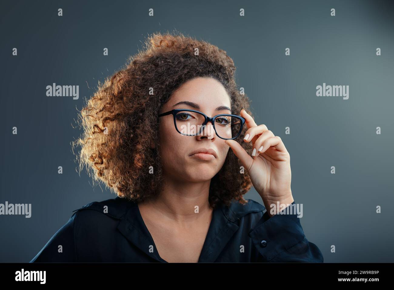 Donna che regola gli occhiali, la sua espressione mescola curiosità con un pizzico di scetticismo Foto Stock