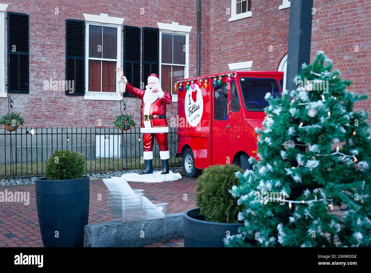 Salem, Massachusetts - Santa Clause tiene una lanterna accanto a un piccolo camion rosso con un cartello con la scritta i Love Fatties decora il patio in mattoni di Foto Stock