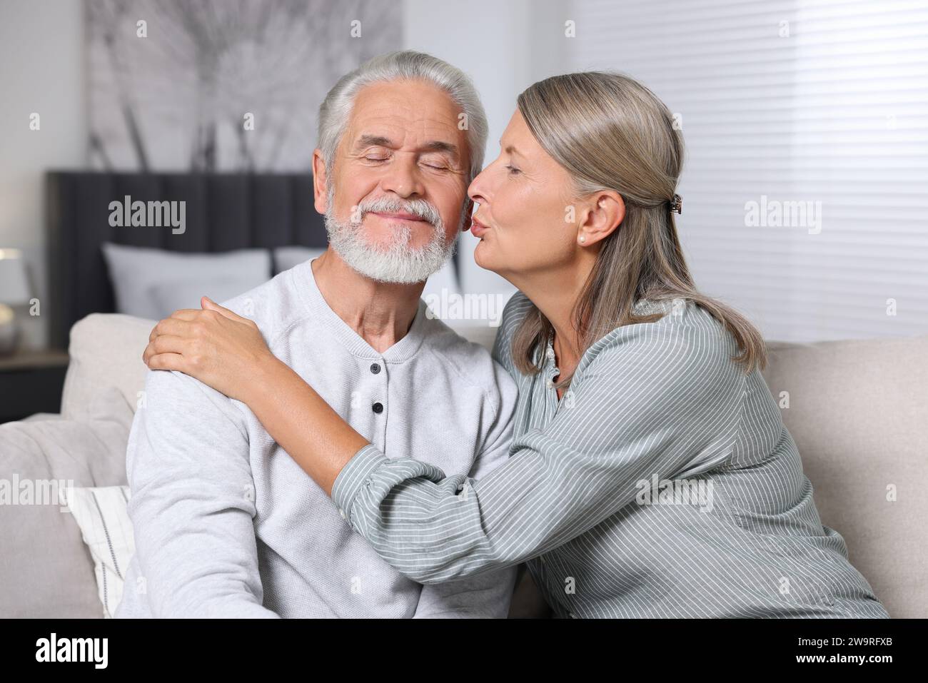 Donna anziana che bacia il suo amato uomo a casa Foto Stock