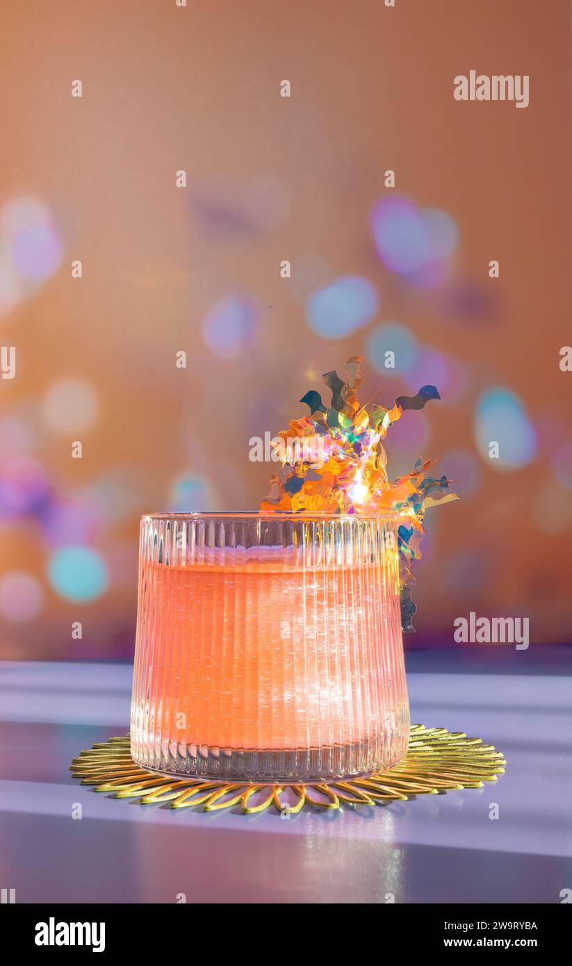Un bel cocktail rosa e arancio con una bibita olografica Swizzle Stick su sfondo bokeh celebrativo ad Orange Foto Stock