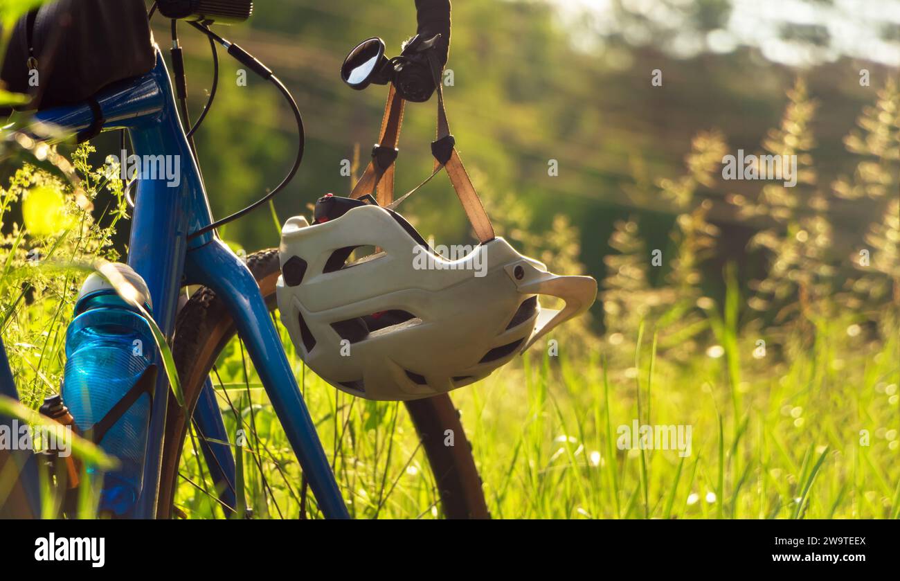 Bicicletta con un casco appeso al manubrio su uno sfondo di erba verde. Primo piano. Foto Stock