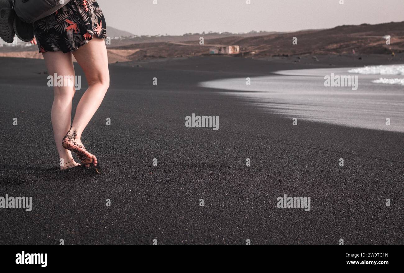 Turista a piedi sulla spiaggia vulcanica nera di Lanzarote, Playa del Janubio Foto Stock