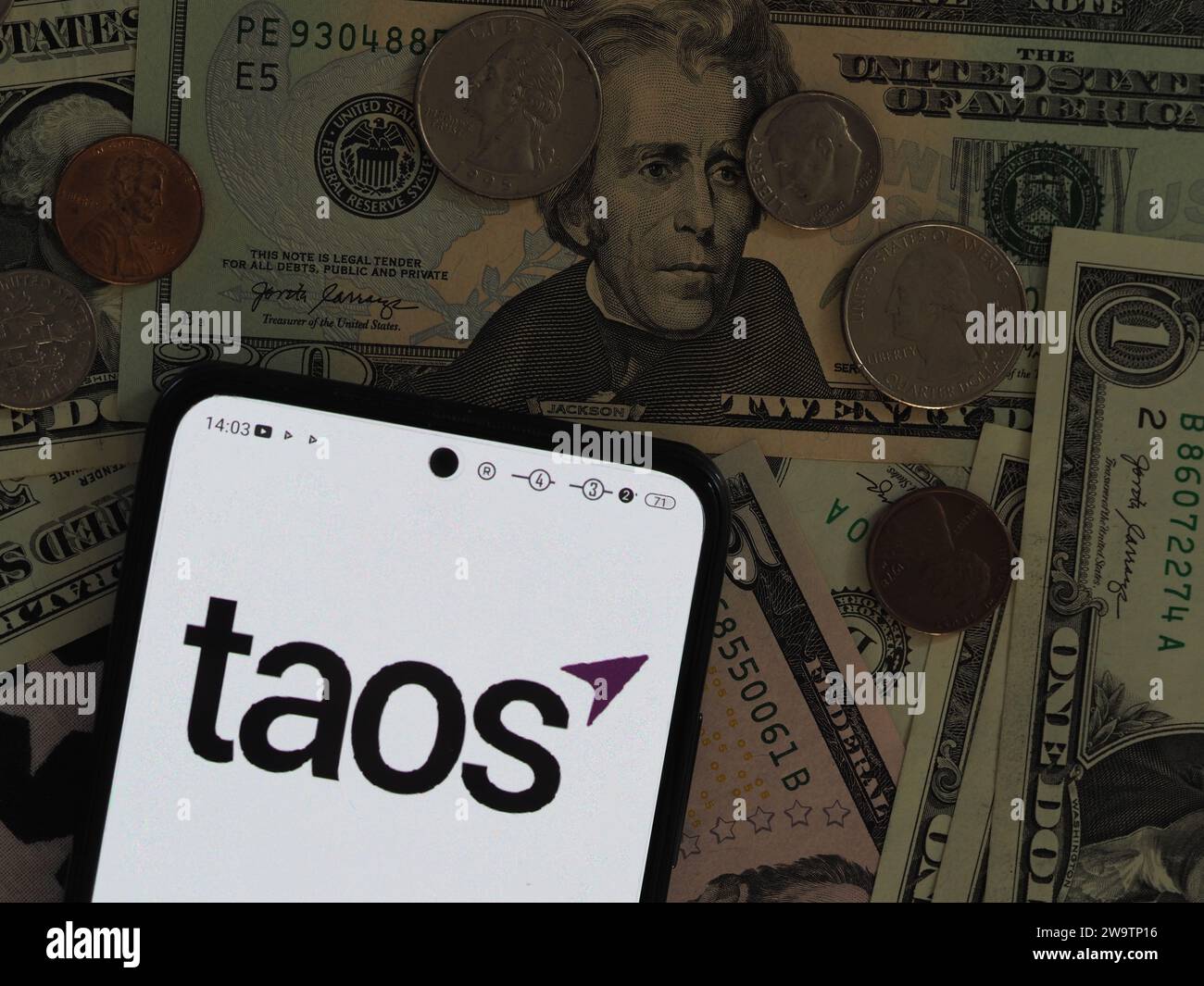 Baviera, Germania - 30 dicembre 2023: In questa immagine, un logo Taos Mountain, Inc. È visibile su uno smartphone con il dollaro degli Stati Uniti Foto Stock