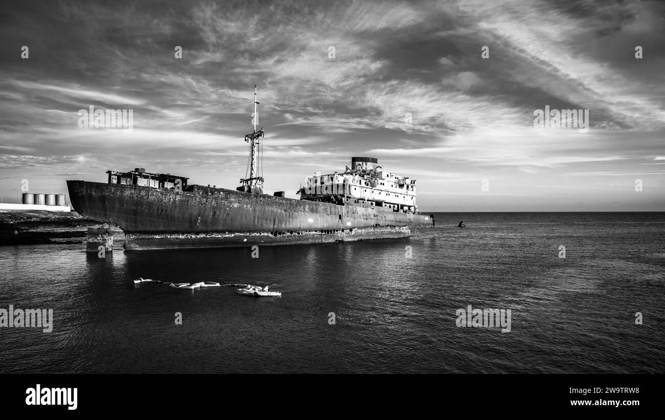 Una nave arrugginita e fatiscente vicino al porto di Arrecife, nelle Isole Canarie. Spagna. Bianco e nero. Foto Stock