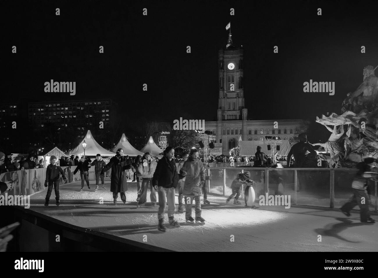12-23-2023 Berlino giovani sulla pista di pattinaggio sul ghiaccio nel centro di Berlino e sulla torre dell'orologio Rotes Rathaus. Le luci blu hanno illuminato le persone e il ghiaccio. Blac Foto Stock