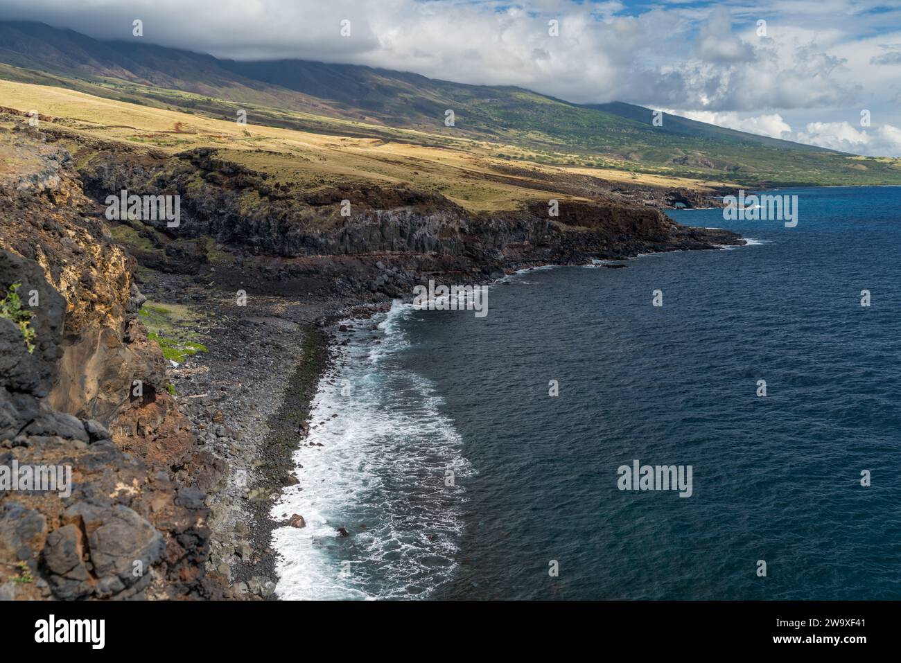Le scogliere di lava torreggiano sulle acque blu profonde di Maui, mostrando il dinamico paesaggio vulcanico dell'isola. Foto Stock