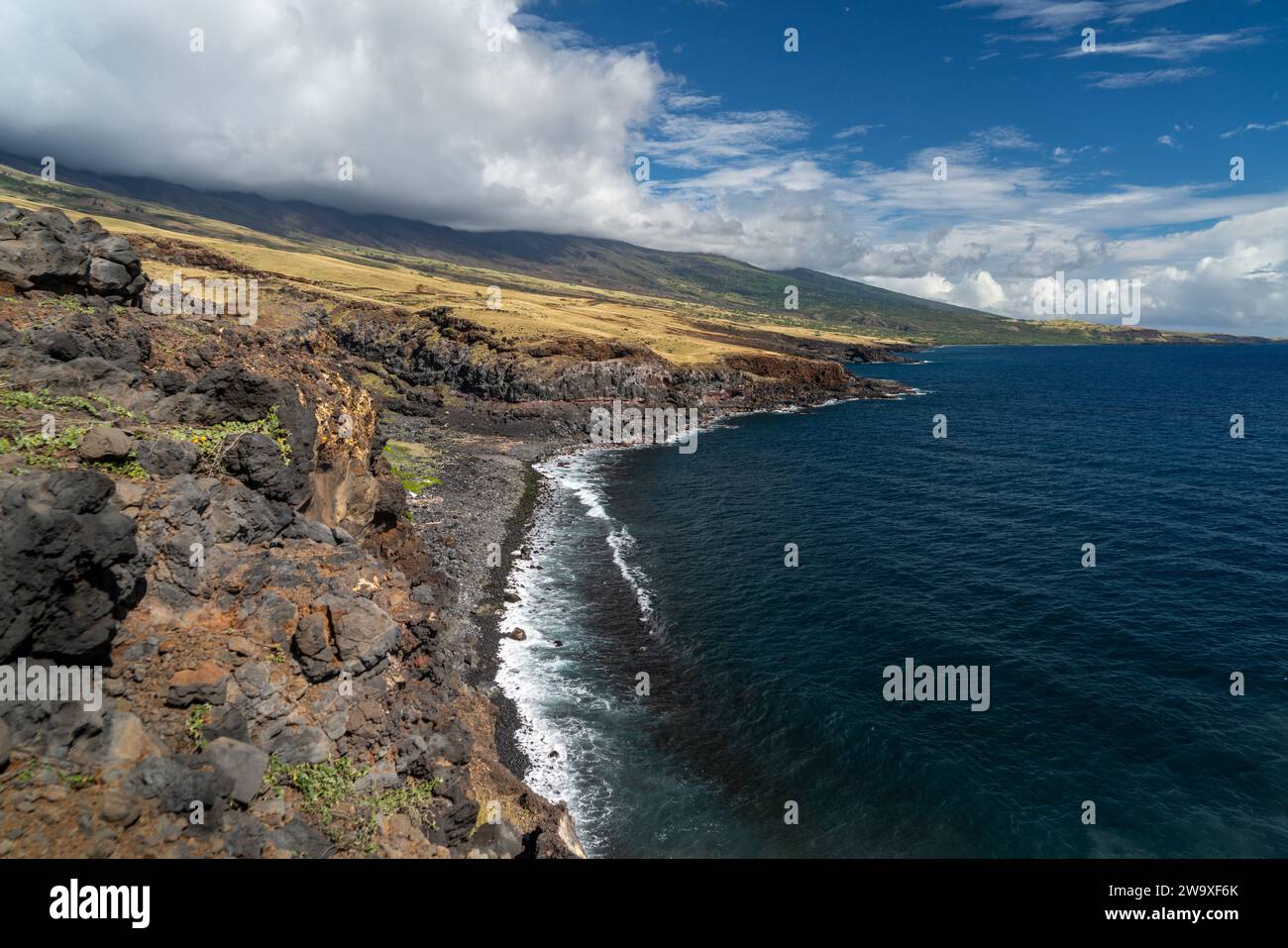 Le scogliere di lava torreggiano sulle acque blu profonde di Maui, mostrando il dinamico paesaggio vulcanico dell'isola. Foto Stock