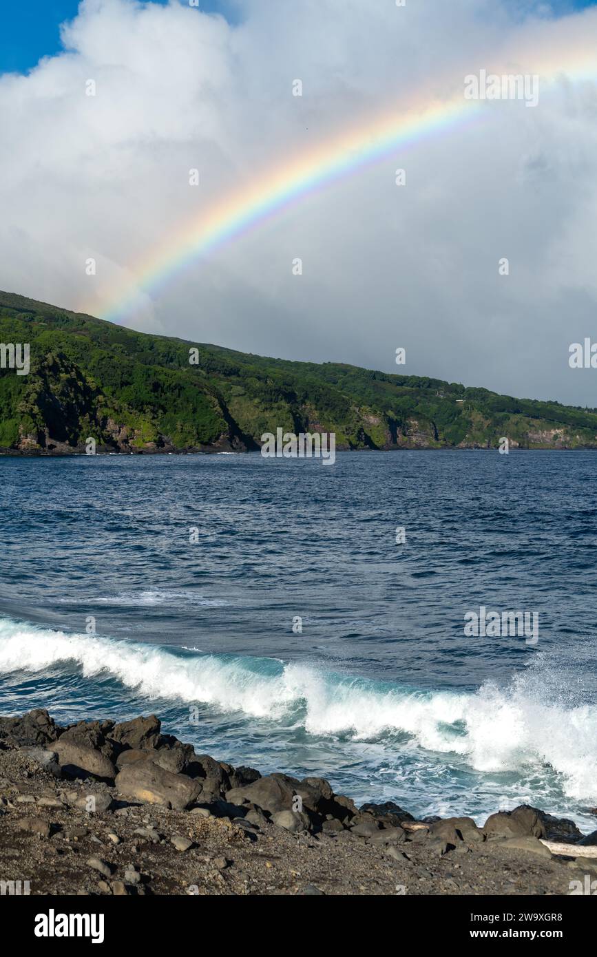 Cattura un arcobaleno impressionante sulle dinamiche onde e sulla costa rocciosa lungo l'autostrada Piilani nel Parco Nazionale di Haleakalā, Maui. Foto Stock