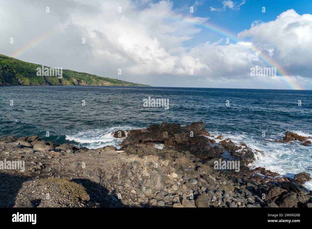 Uno spettacolare arcobaleno incorona lo spruzzo dell'oceano lungo la costa di roccia lavica del Parco Nazionale di Haleakalā, vista dall'autostrada Piilani a Maui. Foto Stock