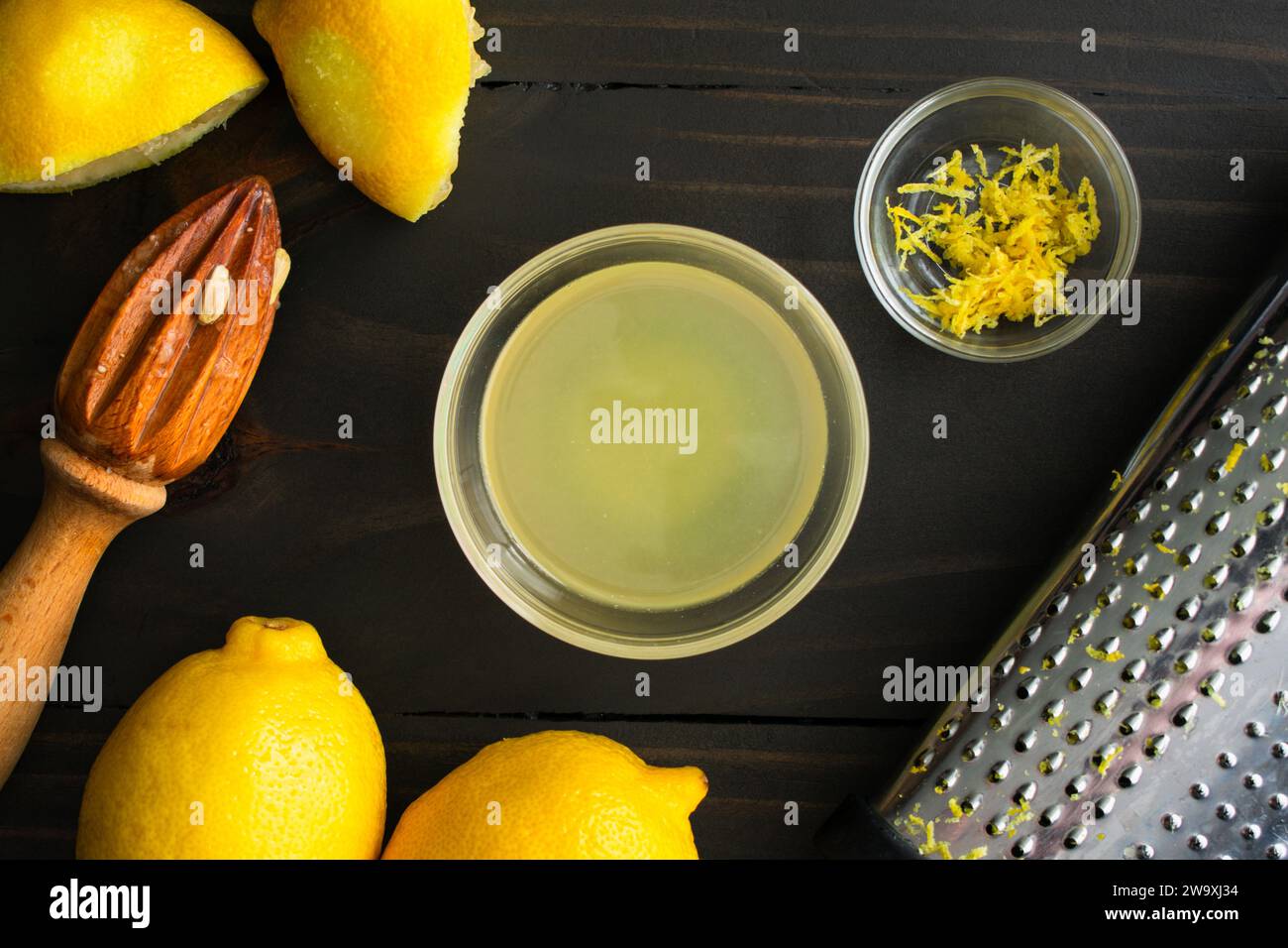 Succo di limone appena spremuto e scorza di limone con utensili da cucina: Succo di limone fresco e scorza di limone con limoni, alesatore di agrumi e grattugia al sacco Foto Stock