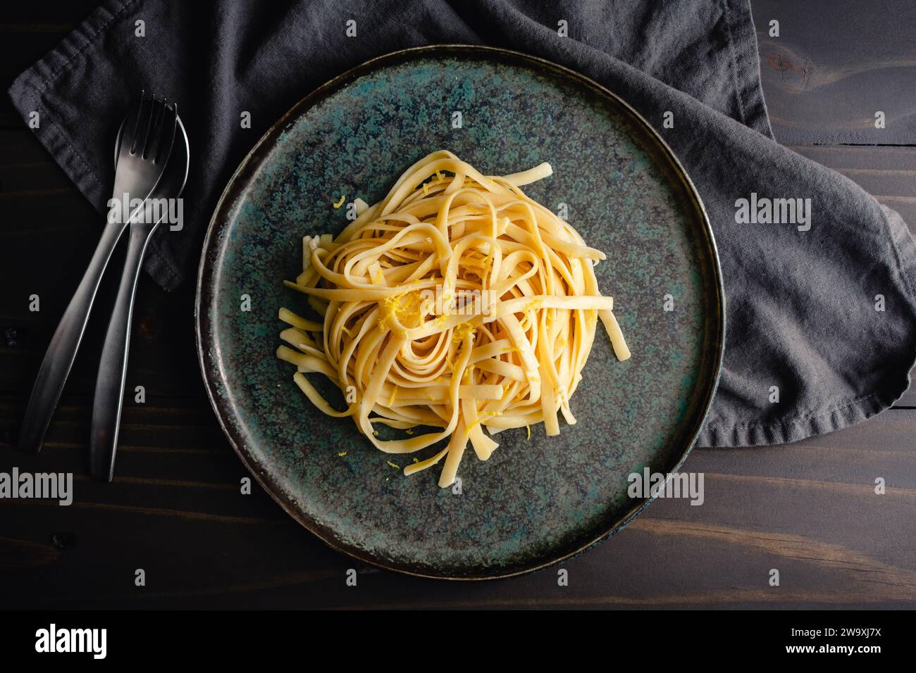 Fettuccine con salsa al limone-mascarpone e scorza di limone: Un piatto di spaghetti larghi serviti guarniti con scorza di limone appena grattugiata Foto Stock
