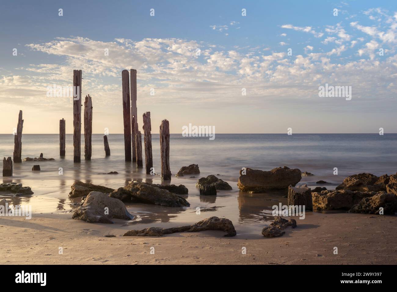 Le rovine del molo sulla spiaggia di Port Willunga nell'Australia meridionale mostrano solo la metà di ciò che rimane e la roccia esposta che brilla con la luce dorata dei tramonti Foto Stock