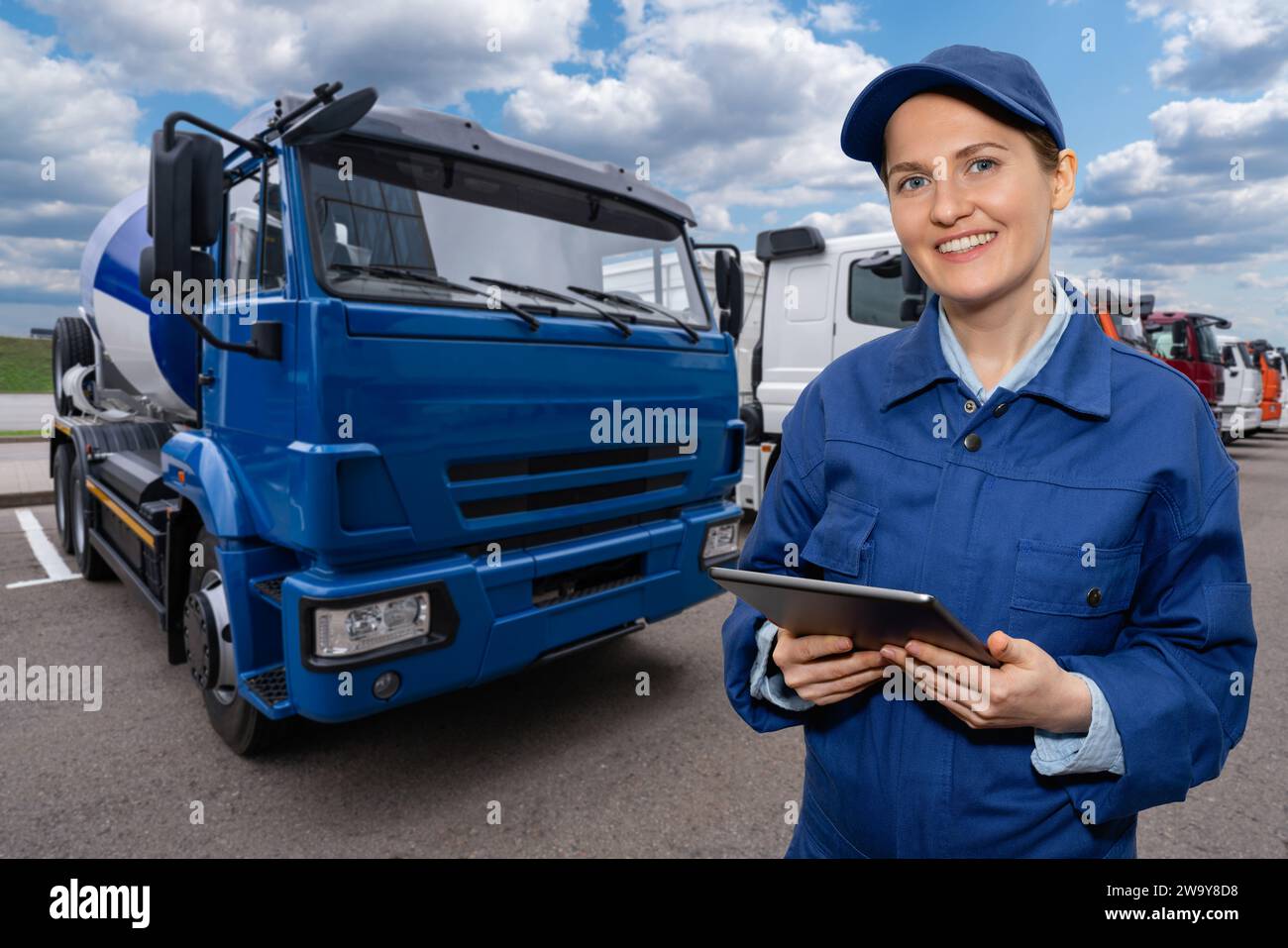 Responsabile donna con un tablet digitale accanto ai veicoli industriali. Gestione della flotta. Foto Stock