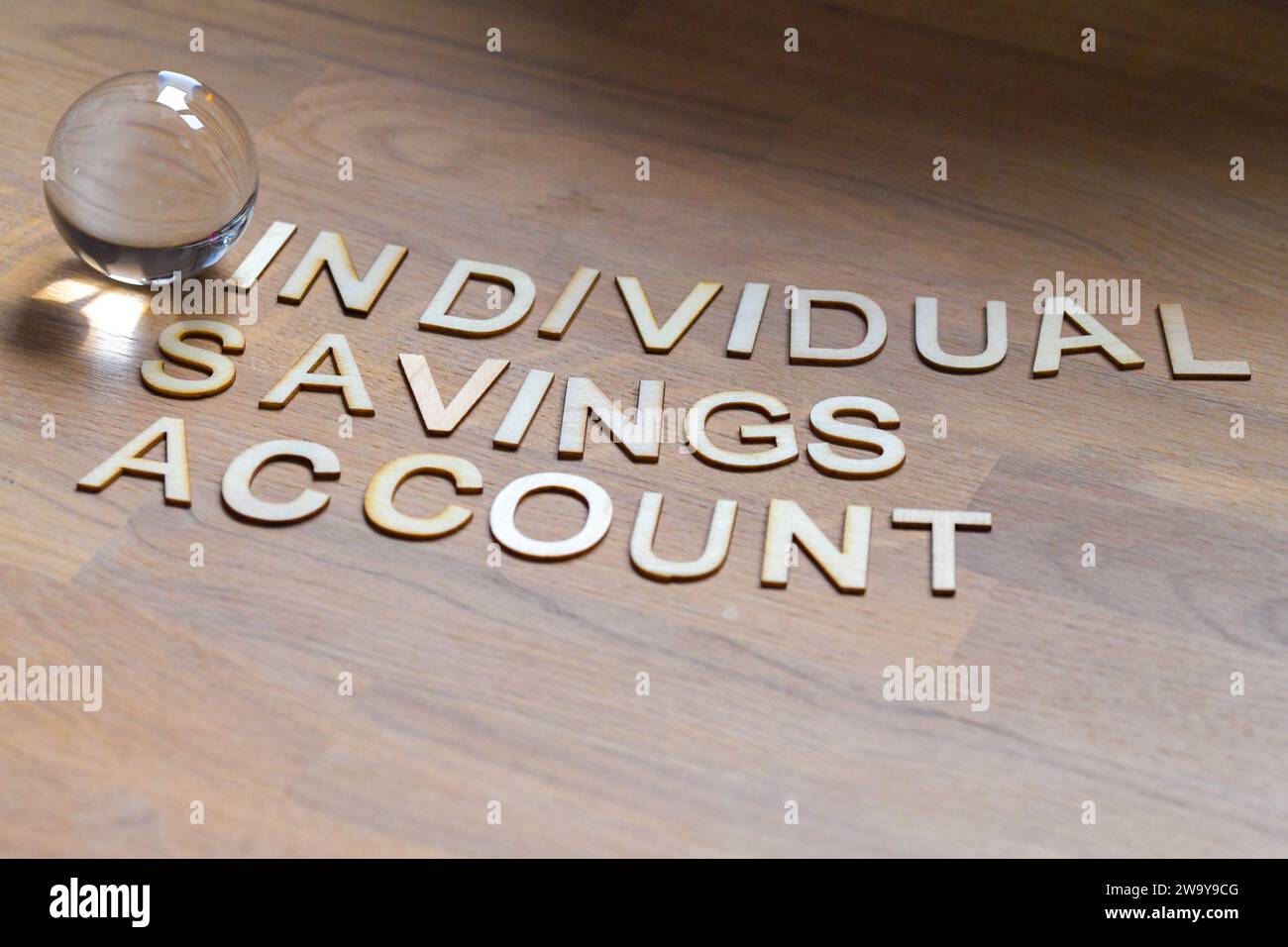 ISA, conto di risparmio individuale in lettere di legno su una superficie di legno con una sfera di cristallo di vetro. il futuro del risparmio Foto Stock