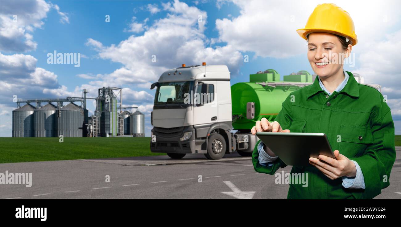 Donna con tablet digitale su sfondo di un veicolo industriale con serbatoio con biocarburante. Foto Stock