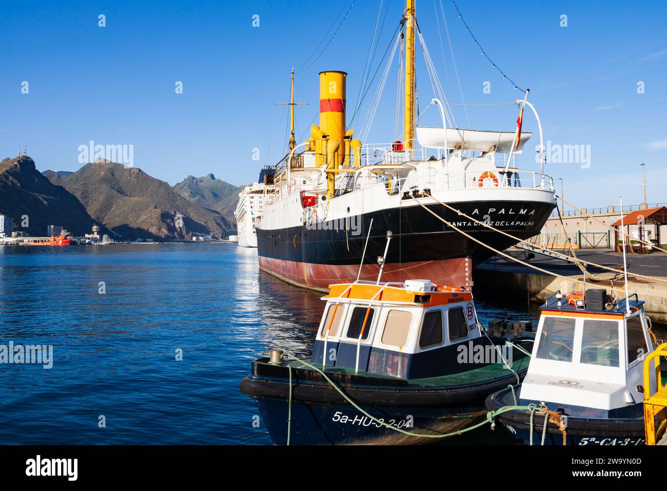 Piccole barche da pesca tradizionali di fronte alla classica nave postale a vapore, la Palma, in fase di restauro presso il terminal delle navi da crociera, il porto di Santa Cruz Foto Stock
