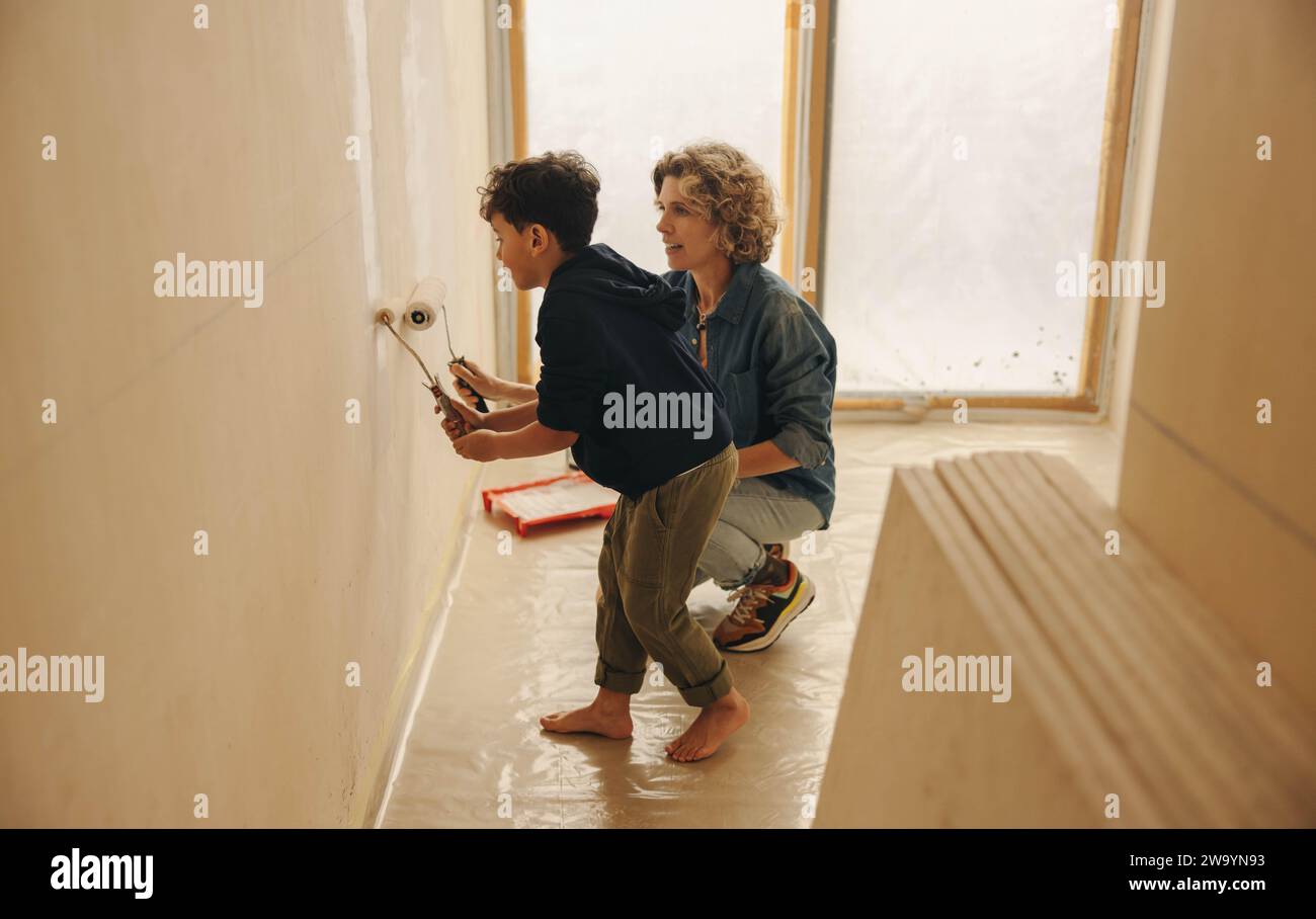 La famiglia creativa del fai da te, tra cui una madre e suo figlio, dipinge le pareti interne della loro casa. Questa attività di ristrutturazione della casa al coperto mostra il Foto Stock