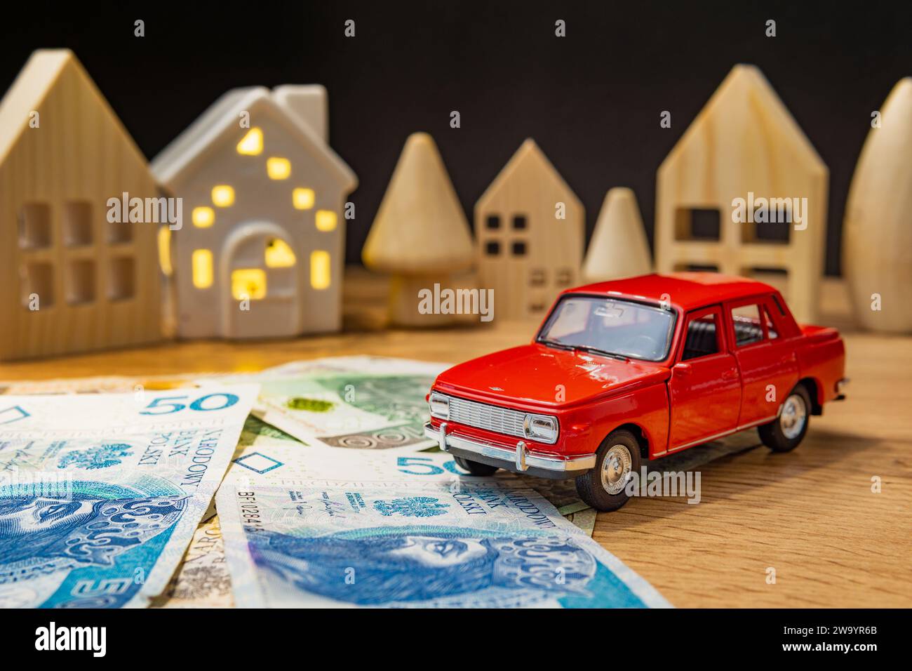 auto giocattolo con soldi polacchi e casa di legno che aumentano le spese per la vita crisi di inflazione tasso di interesse del prestito auto concetto Foto Stock
