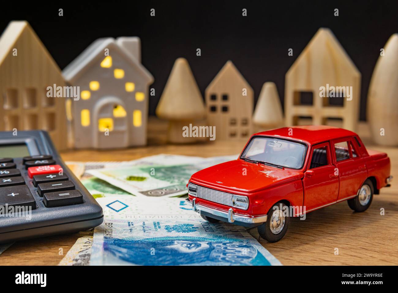 auto giocattolo con soldi polacchi, calcolatrice e casa di legno che aumentano le spese di vita inflazione crisi concetto auto tasso di interesse prestito Foto Stock