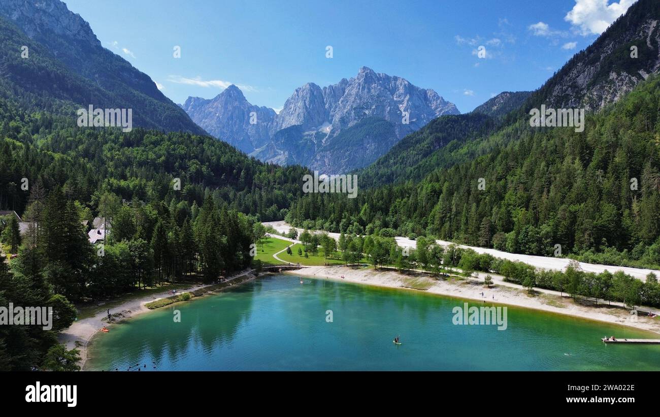Vista aerea con drone delle acque glaciali alpine del lago Jasna, molo riflettente e picchi circostanti a Kranjska Gora, Alpi Giulie, Slovenia. Foto Stock