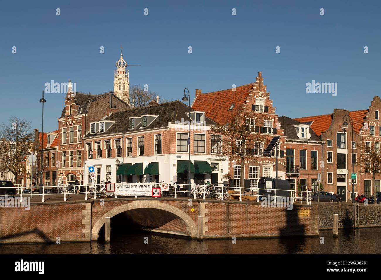 Case sul canale lungo il fiume Spaarne con la torre del Bakenesserkerk sullo sfondo nella città olandese di Haarlem. Foto Stock