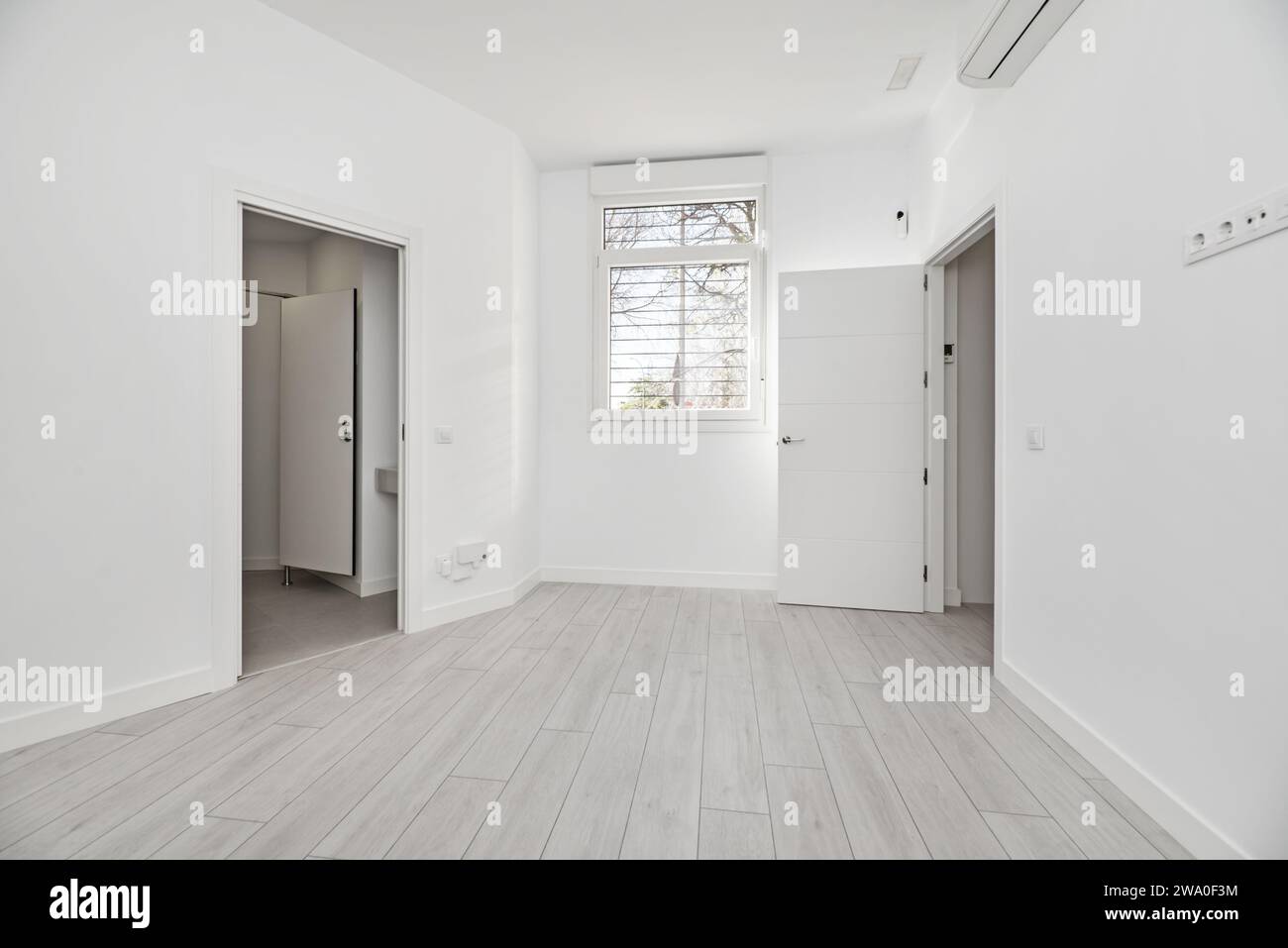 Una camera in una casa in stile loft al piano terra con pavimenti in legno chiaro, finestre in alluminio bianco con bar e aria condizionata Foto Stock