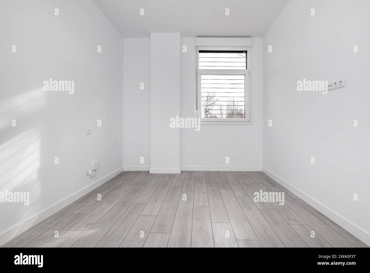 Una camera vuota in una casa in stile loft al piano terra con pavimenti in legno chiaro e una finestra in alluminio bianco con barre di metallo Foto Stock