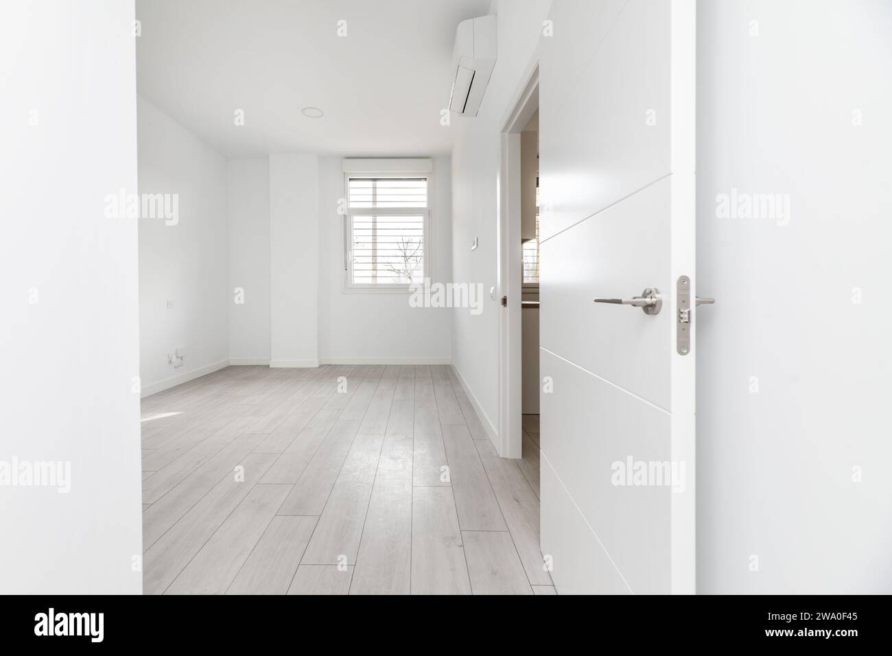 Corridoio di una casa con una stanza vuota in una casa di tipo loft al piano terra con pavimenti in legno chiaro e porte di accesso ad altre camere Foto Stock