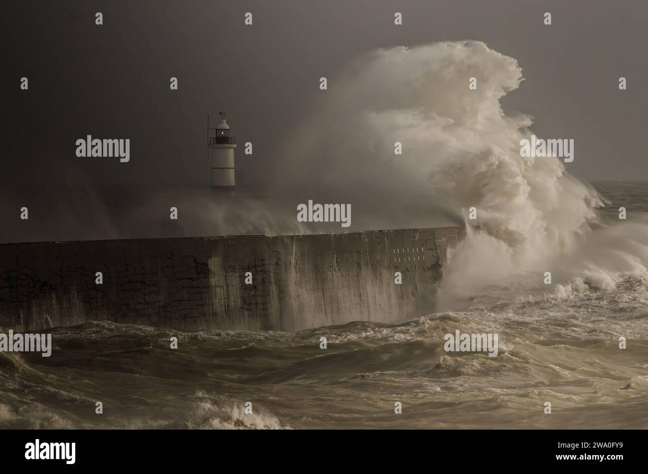 Newhaven. East Sussex, Regno Unito. 31 dicembre 2023. Il 2023 parte con un'esplosione tempestosa, mentre il vento del Sud-Ovest spinge il mare al largo della costa del Sussex in una frenesia creando scene spettacolari. Gli ultimi raggi di luce catturano un'onda mentre le nuvole scure avvolgono la scena. Credito: David Burr/Alamy Live News Foto Stock