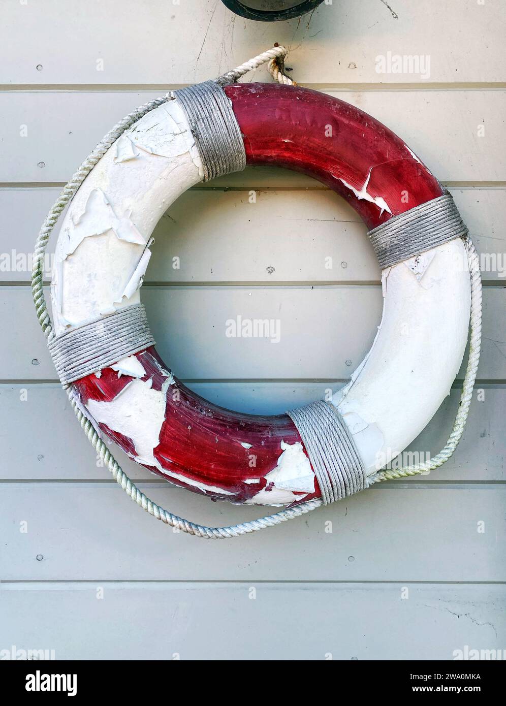 Un anello salvagente rosso e bianco, salvagente o salvagente appeso a un muro vicino alla spiaggia in estate Foto Stock