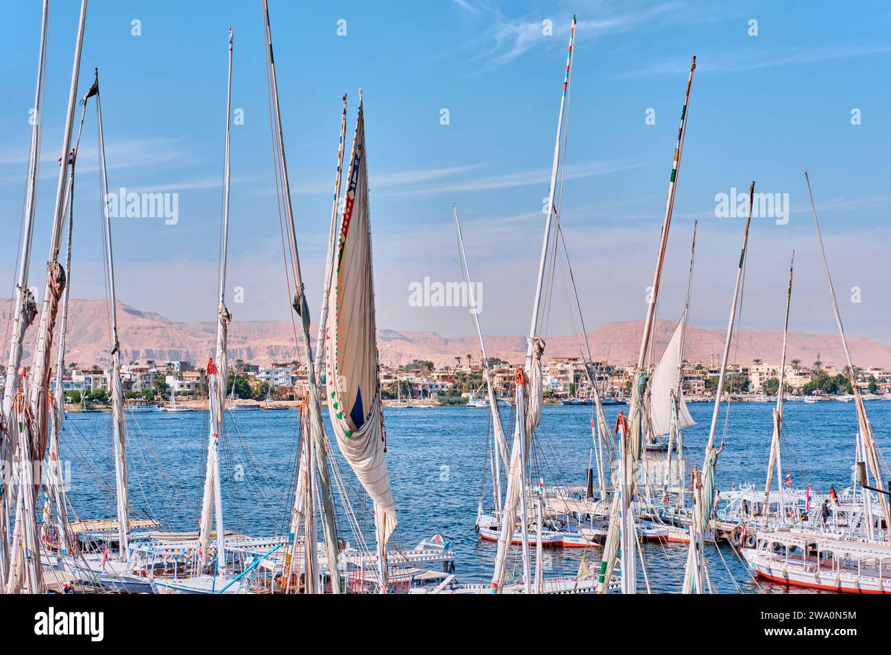 Luxor, Egitto - dicembre 26 2023: Tradizionali traghetti a motore e barche a vela in feluca ormeggiate lungo il Nilo Foto Stock