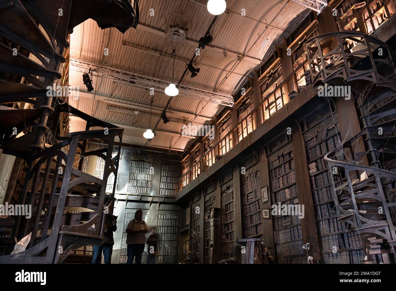 La biblioteca con vecchie librerie e una scala a chiocciola, progettata dall'artista Rone. Esplora il rapporto sinergico tra bellezza, decadimento e. Foto Stock