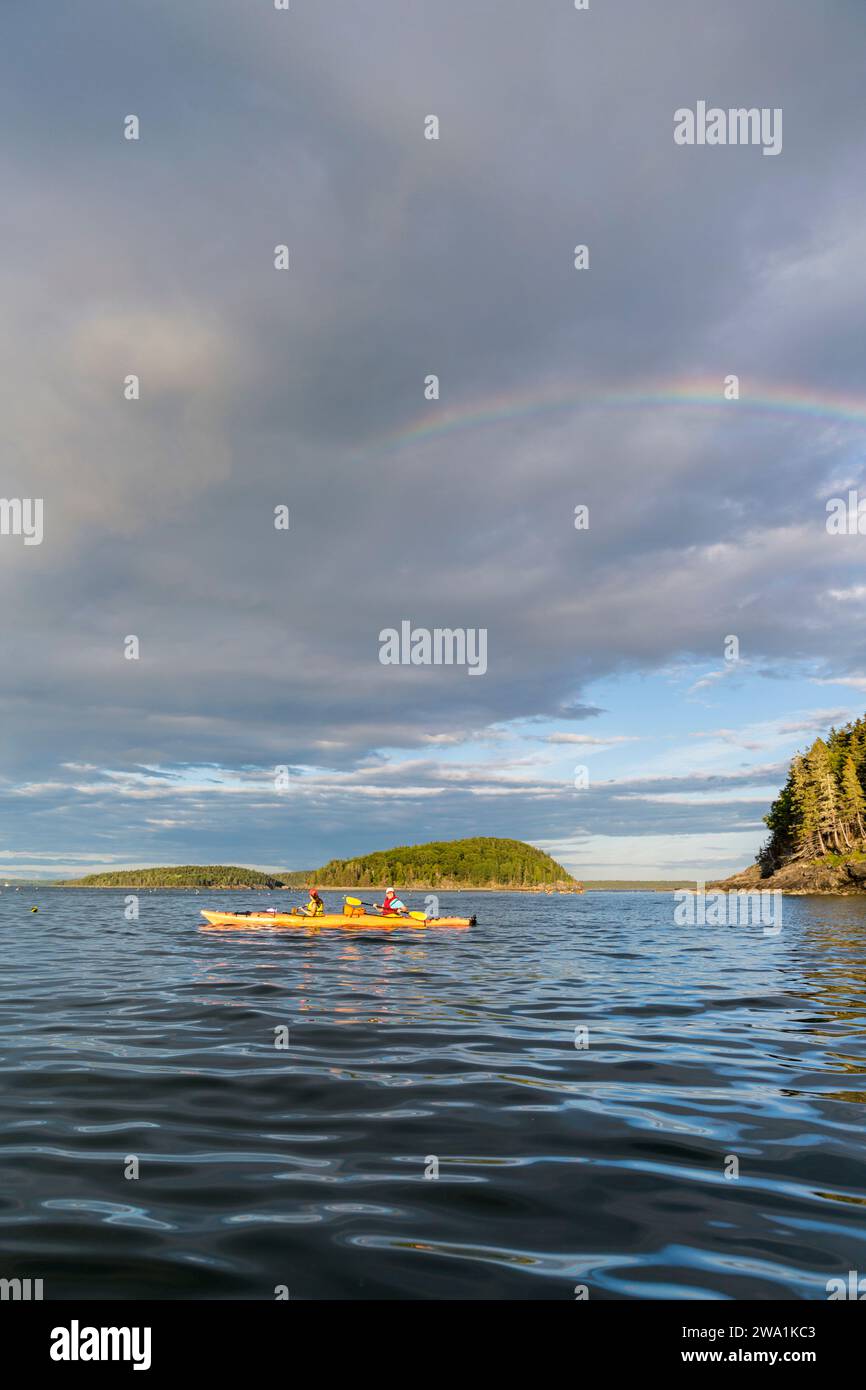 Una donna e sua figlia vanno in kayak sotto un arcobaleno a Frenchman Bay, Acadia National Park, Maine. Porcupine Islands. Foto Stock